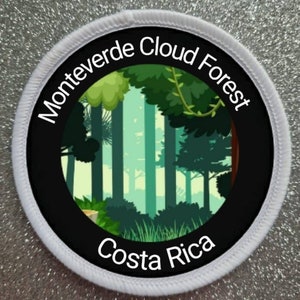 May include: A white round patch with black text and a black circle in the centre. The text reads "Monteverde Cloud Forest Costa Rica". The circle contains a cartoon image of a green forest.