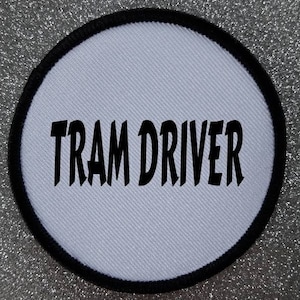 May include: White round patch with black border and the text "TRAM DRIVER" in black.