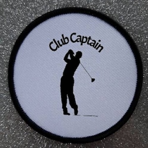 May include: White round embroidered patch with black trim. The patch features a silhouette of a golfer swinging a club and the text "Club Captain".
