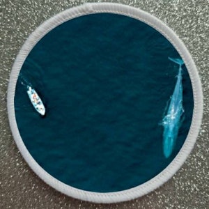 May include: A white boat with people in it is sailing on a deep blue ocean. A large whale is swimming in the water below the boat.