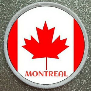 Op de afbeelding: Een ronde witte en rode patch met een rood esdoornblad en het woord "MONTREAL" in zwarte tekst.