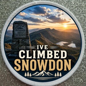 Puede incluir: Un parche circular con un paisaje montañoso y el texto "I'VE CLIMBED SNOWDON". El parche presenta un marcador de piedra con "SNOWDON" y la altura en metros. El diseño incluye una puesta de sol, montañas y árboles.