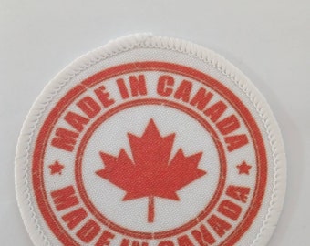 May include: A white round patch with a red circle and the text "Made in Canada" around the outside. A red maple leaf is in the center of the circle.