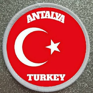 Può includere: Toppa rotonda con la bandiera turca, con sfondo rosso, una luna crescente bianca e una stella bianca. Le parole "ANTALYA" e "TURKEY" sono in bianco, a forma di arco.