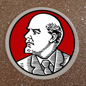 Könnte beinhalten: Ein roter Kreis-Patch mit einer Schwarz-Weiß-Illustration eines Männergesichts. Der Mann hat einen Schnurrbart und trägt einen Anzug.