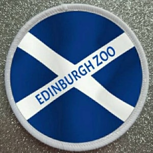 May include: A white and blue round patch with the text "EDINBURGH ZOO" in white letters on a blue background. The patch has a white border.