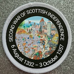 Könnte beinhalten: Ein weißer runder Patch mit einem schwarzen Kreis in der Mitte. Der schwarze Kreis enthält weißen Text, der "Second War of Scottish Independence 6 August 1332 - 3 October 1357" lautet. Im Inneren des schwarzen Kreises befindet sich eine farbige Illustration einer mittelalterlichen Kampfszene.