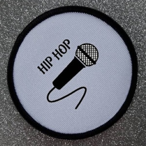 May include: White round patch with a black border. The patch has a black microphone with a cord and the text "HIP HOP" in black.