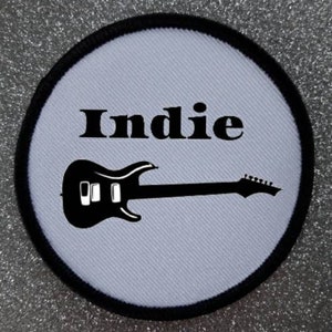 May include: White round patch with black stitching around the edge. The patch has a black electric guitar and the word "Indie" in black text.