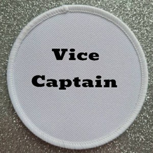 May include: White round fabric patch with black text that reads "Vice Captain".