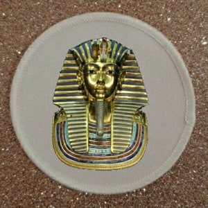May include: A gold and blue pharaoh mask with a white background. The mask is detailed with intricate patterns and a crown.