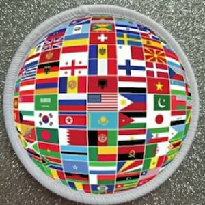Könnte beinhalten: Ein weißer runder Patch mit einem Globus-Design, das eine Vielzahl von Flaggen aus verschiedenen Ländern zeigt. Die Flaggen sind in einem Raster angeordnet und bedecken die gesamte Oberfläche des Globus.