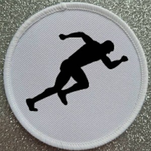 Op de afbeelding: Witte ronde patch met een zwart silhouet van een hardloper in startpositie.