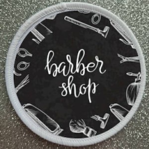 May include: White round patch with a black background and white text that says "barber shop". The background is filled with white illustrations of barber tools.