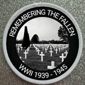 May include: Black and white patch with the text "Remembering the Fallen WWII 1939-1945" and a picture of a cemetery with rows of white crosses.