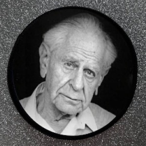 Könnte beinhalten: Schwarzweiß-Porträtfotografie eines älteren Mannes mit weißem Haar. Er trägt ein weißes Hemd und hat einen ernsten Gesichtsausdruck.