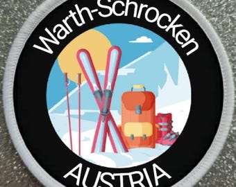 Könnte beinhalten: Ein runder, weiß umrandeter Aufnäher mit schwarzem Hintergrund. Der Aufnäher zeigt eine bunte Illustration einer verschneiten Berglandschaft mit Skiern, Skistöcken, einem Rucksack und Skischuhen. Der Text "Warth-Schrocken" ist in einem weißen Kreis um das Bild geschrieben, und der Text "AUSTRIA" ist in einem weißen Kreis unter dem Bild geschrieben.