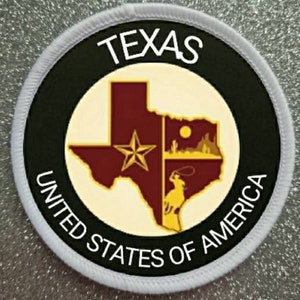 Może przedstawiać: Biała okrągła łatka z czarną obwódką i białym tekstem. Tekst brzmi "TEXAS UNITED STATES OF AMERICA". Wewnątrz obwódki znajduje się żółty zarys stanu Teksas z czerwoną gwiazdą i czerwono-żółto-brązowym wzorem wewnątrz zarysu.