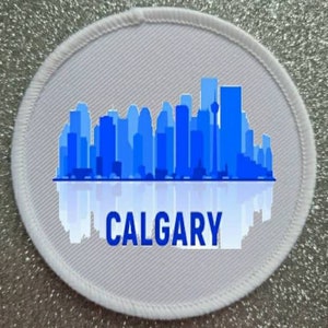 May include: White round patch with a blue silhouette of the Calgary skyline and the word "CALGARY" in blue letters.