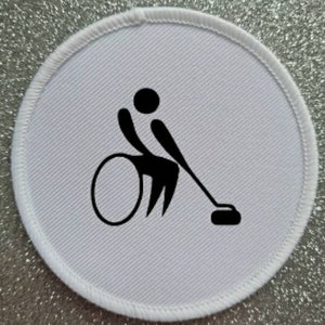May include: White round patch with a black silhouette of a person in a wheelchair playing wheelchair curling.