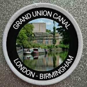 May include: A white and black round patch with the text "Grand Union Canal London - Birmingham" and a photo of a canal with boats.