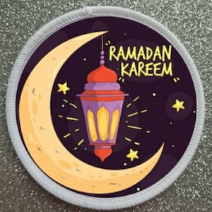 May include: A white round patch with a crescent moon and a purple and orange lantern with the text "Ramadan Kareem" in yellow.