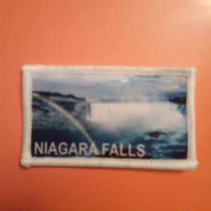 May include: White embroidered patch with a photo of Niagara Falls and the text "NIAGARA FALLS".