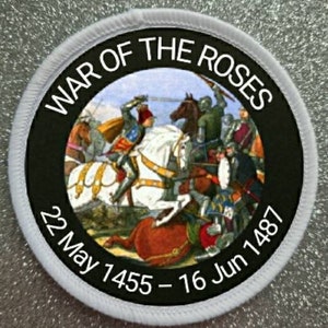 Può includere: Un cerotto circolare bianco con testo nero e un'immagine colorata di una scena di battaglia. Il testo recita "War of the Roses 22 May 1455 - 16 Jun 1487".