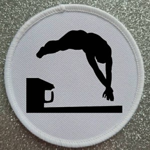 May include: A white round patch with a black silhouette of a person diving off a diving board. The person is in mid-air, arms extended, and legs together. The diving board is a simple rectangle.