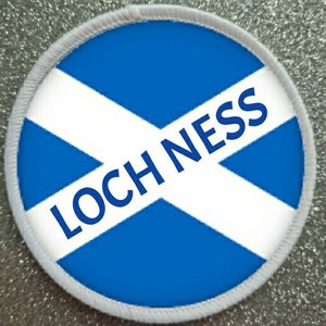 May include: A white and blue round patch with a white diagonal cross and the text "LOCH NESS" in blue letters.