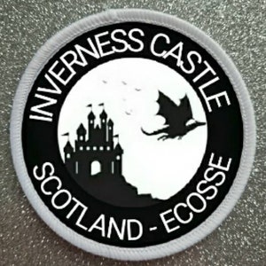 May include: A white and black round patch with the text "Inverness Castle Scotland - Ecosse" around the edge. The center of the patch features a black silhouette of a castle and a dragon.