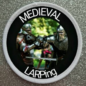 May include: A white and black circular patch with the text "MEDIEVAL LARPING" in white lettering. The patch features a photo of two people in medieval armor fighting with swords in a forest setting.