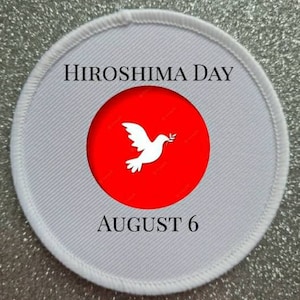 May include: White round patch with red circle in the center. The red circle has a white dove with an olive branch in its beak. The text "HIROSHIMA DAY AUGUST 6" is printed in black on the white patch.