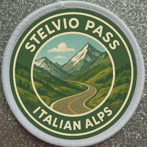 May include: A round patch with a scenic illustration of the Stelvio Pass in the Italian Alps. The design features a winding road through green mountains, snow-capped peaks, and a blue sky with clouds. The text "STELVIO PASS" and "ITALIAN ALPS" are in white.