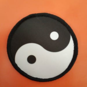 May include: Black and white yin yang symbol patch with a black border. The patch is circular and has a white background with a black yin yang symbol in the center.