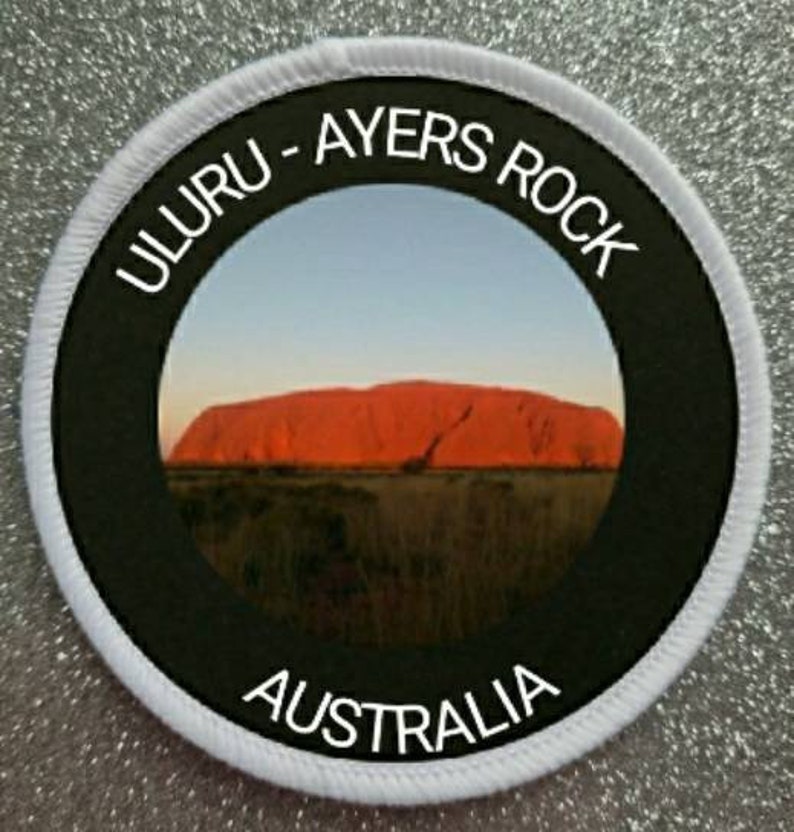 May include: A white and black round patch with the text "Uluru - Ayers Rock Australia" around a photo of Uluru, a large red rock formation in Australia.