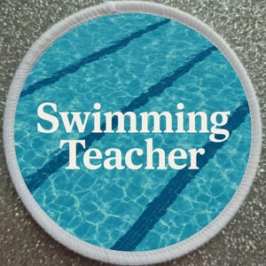 May include: A circular patch featuring the text "Swimming Teacher" in white, set against a blue pool water background. Dark blue lines represent swimming lanes, with a white border.