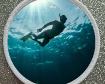Könnte beinhalten: Eine Silhouette einer Person beim Schnorcheln in einem blauen Meer mit Sonnenlicht, das durch das Wasser scheint.
