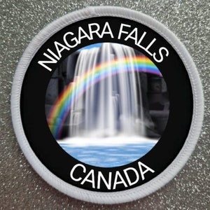 May include: A round white patch with a black circle in the center. The circle has the words "NIAGARA FALLS CANADA" around the edge. Inside the circle is a photo of Niagara Falls with a rainbow over the falls.