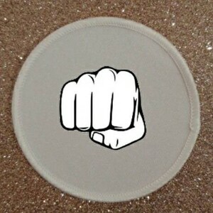 May include: White round patch with a black and white illustration of a fist.