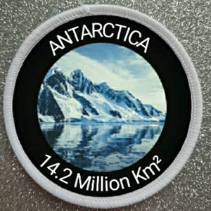 Könnte beinhalten: Ein weißer runder Patch mit einem schwarzen Kreis in der Mitte. Der Kreis enthält ein Bild einer schneebedeckten Bergkette mit einem Gewässer im Vordergrund. Der Text "ANTARCTICA" ist in Weiß um den oberen Rand des schwarzen Kreises geschrieben. Der Text "14.2 Million Km2" ist in Weiß am unteren Rand des schwarzen Kreises geschrieben.