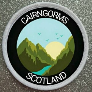 May include: White round patch with black border and a mountain scene inside. The text "CAIRNGORMS SCOTLAND" is printed in white around the border.