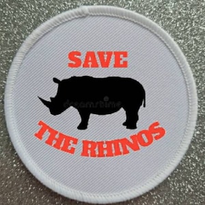 May include: White round fabric patch with a black silhouette of a rhinoceros and the text "SAVE THE RHINOS" in red.