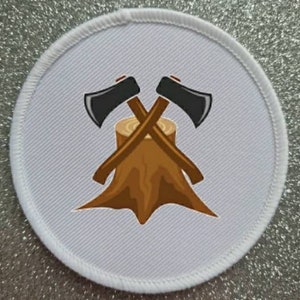 Op de afbeelding: Een witte ronde patch met een bruine boomstronk en twee zwarte gekruiste bijlen erop. De bijlen hebben zwarte handvatten.