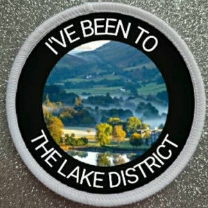 May include: White round patch with a black border and white text that reads "I've Been To The Lake District". The patch features a scenic image of a lake and hills in the background.