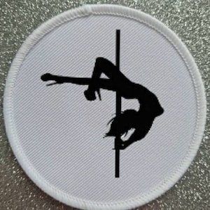 May include: A white round patch with a black silhouette of a person on a pole. The person is in a pose that is often associated with pole dancing.