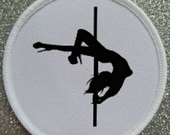 May include: A white round patch with a black silhouette of a person on a pole. The person is in a pose that is often associated with pole dancing.