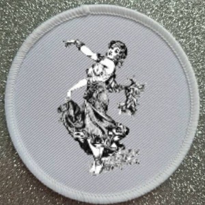 May include: A white embroidered patch featuring a black and white image of a woman dancing in a flowing dress.