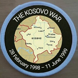 May include: A blue and black circular patch with the text "THE KOSOVO WAR" and a map of Kosovo. The dates "28 February 1998 - 11 June 1999" are printed below the map.