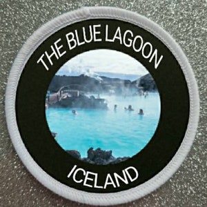 Op de afbeelding: Een witte ronde patch met zwarte tekst en een foto van de Blue Lagoon in IJsland. De tekst luidt "The Blue Lagoon Iceland".